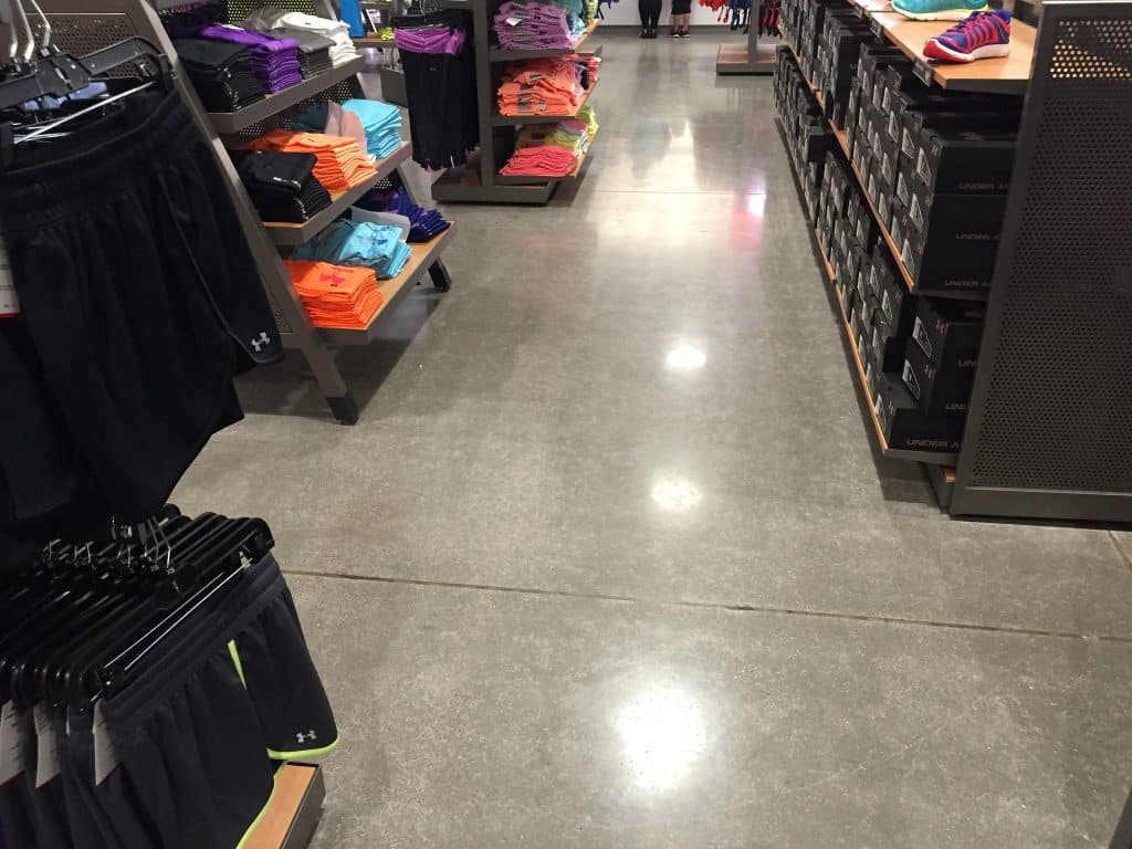 Image of a retail store with polished concrete floors, featuring racks and shelves of clothing and a modern, minimalist design aesthetic.