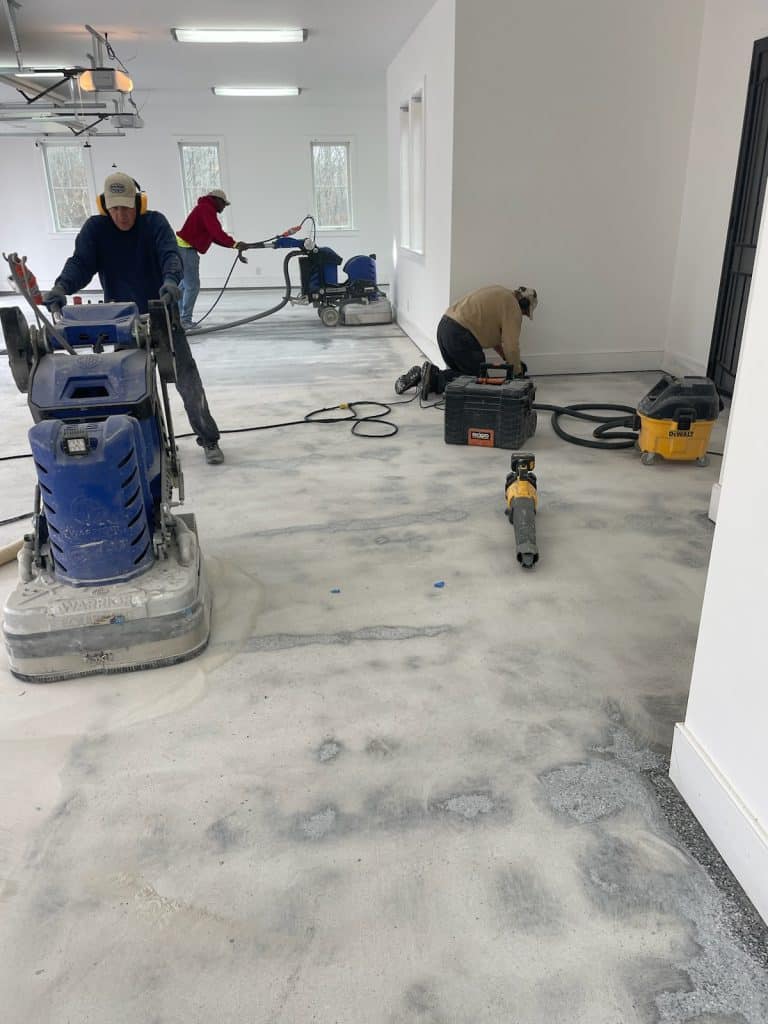 Image of a contractor using a large grinder to smooth and level a concrete floor surface, creating a uniform and level finish.